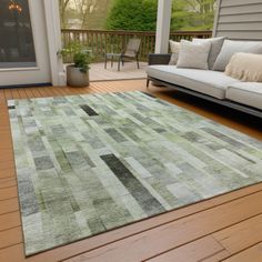 a living room area with couches and rugs on the wooden flooring outside