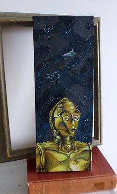 a painting of a gold robot on a wooden block