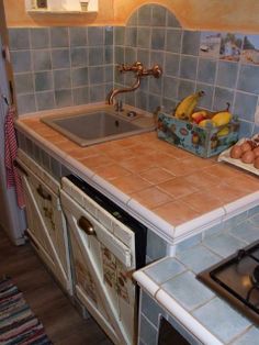 a kitchen with blue tiled walls and counter tops, including a stove top oven and sink