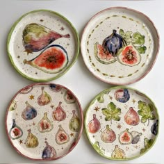 four plates with different designs on them sitting next to each other and one has an eggplant