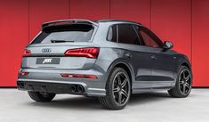 the rear end of an audi suv parked in front of a red wall with black rims