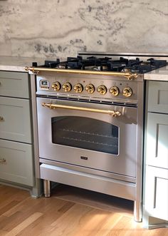 a silver stove top oven sitting inside of a kitchen next to wooden floors and cabinets