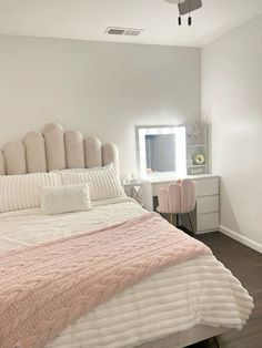 a bedroom with a bed, dresser and mirror in the corner that has a pink blanket on it