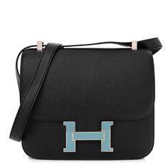 This is an authentic HERMES Epsom Enamel Constance 24 in Black and Blue Saint Cyr. This stylish shoulder bag is crafted of fine textured epsom calfskin leather in black. This chic bag features a uniquely constructed looping shoulder strap with polished palladium links and a top flap that tucks into a prominent H in palladium hardware and blue enamel. This opens to a partitioned lambskin leather interior with a zipper and patch pocket. This is an excellent shoulder bag, ideal for everyday wear, from Hermes! Stylish Shoulder Bag, Chic Bags, Leather Interior, Lambskin Leather, Patch Pocket, Calf Skin, Blue Black, Everyday Wear, Shoulder Strap