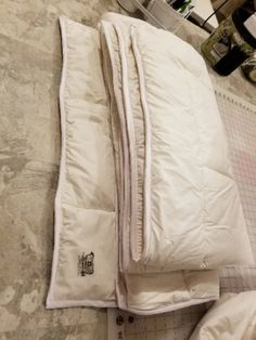 a pile of white blankets sitting on top of a floor next to a cutting board