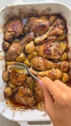 someone spooning some food out of a casserole dish with chicken and potatoes