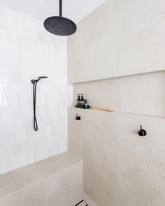 a shower head and faucet in a white tiled bathroom with black fixtures on the wall