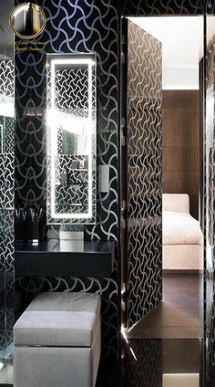 a bathroom with black and white wallpaper has a bench in front of the mirror