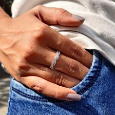 a woman's hand with a wedding ring on her left finger, wearing jeans and a white t - shirt