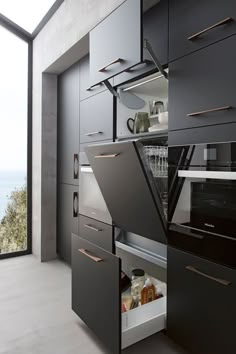 an open drawer in the middle of a kitchen next to a wall with glass doors