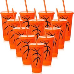 many orange cups with black designs and straws on them are lined up in a row