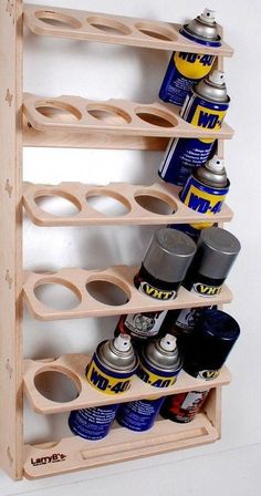 a wooden rack with cans and cans on it's sides, holding several different types of spray paint