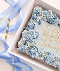 a birthday cake in a box with blue streamers around it and the words happy birthday