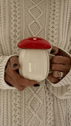 a woman holding a cup in her hands with a red lid on it's side