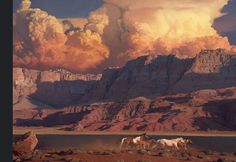 two horses are standing in the desert with mountains and clouds behind them, as the sun sets