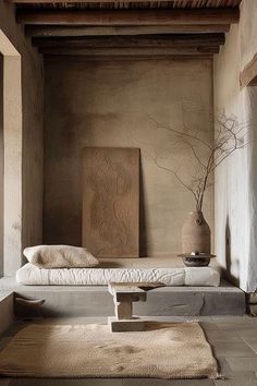 a bed sitting in the middle of a room next to a vase on top of a table