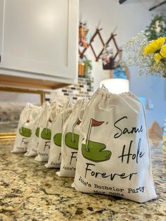 four bags are lined up on the counter in front of a vase with yellow flowers