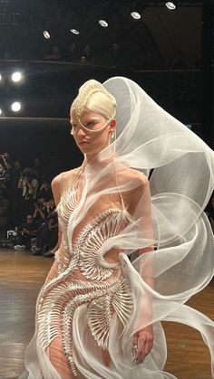 a woman in a white dress and veil on the runway