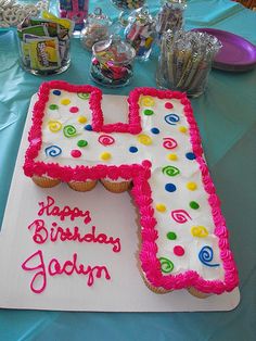 a birthday cake shaped like the letter h on a table with candy and candies