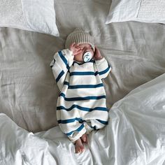 a baby laying on top of a bed covered in white sheets and pillows with a pacifier