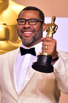 a man in a tuxedo holding an oscar statue