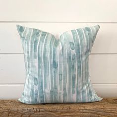 a blue and white striped pillow sitting on top of a wooden table next to a wall