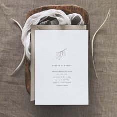 the wedding stationery is laid out on top of a wooden tray with white paper