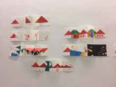 several pieces of paper cut into shapes with houses and mountains in the background on a white wall