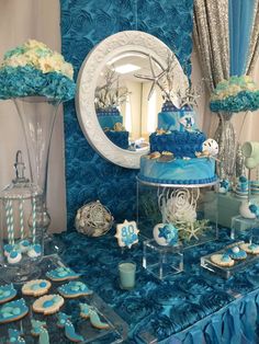 a table with blue and white desserts, cookies and cupcakes on it