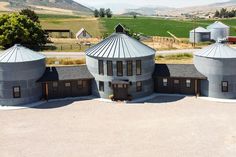 an aerial view of three large silos in the middle of a rural area with mountains in the background