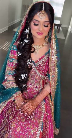 a woman in a pink and green bridal outfit with her hands on her hips