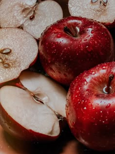 an apple sliced in half and sitting on top of some other apples with water droplets