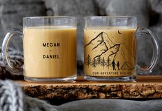 two coffee mugs sitting on top of a wooden table next to a gray blanket