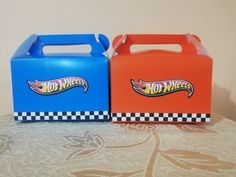 two boxes with hot wheels logos on them are sitting on a tablecloth covered surface