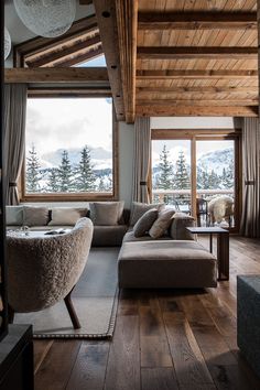 a living room filled with furniture and a large window covered in snow capped mountains behind it