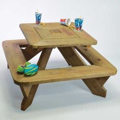 a wooden picnic table with two benches and cups on the top, in front of a white background