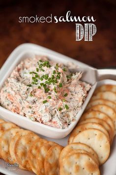 smoked salmon dip with crackers and parsley in a white bowl on a plate