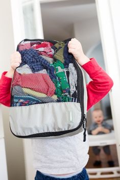 a young child holding up a piece of luggage