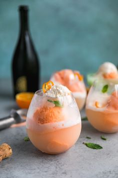 three wine glasses filled with drinks and garnished with orange peels on the side