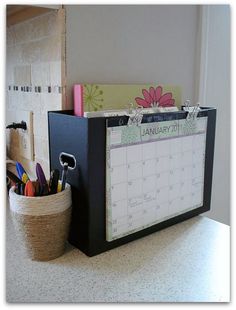 a desk with a calendar, pen holder and other office supplies on it's side