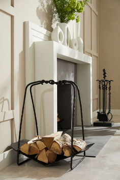 a firewood rack with logs in front of a fireplace and potted plant on top