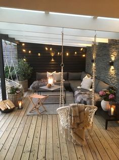 an outdoor living area with wooden flooring and lights strung from the ceiling above it