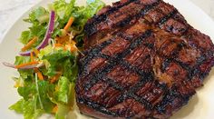 a steak and salad on a white plate