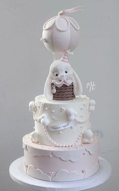 a three tiered cake with white frosting and pink icing, topped with an umbrella