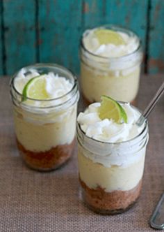 three small mason jars filled with key lime cheesecakes and topped with whipped cream