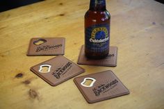 three beer coasters sitting on top of a wooden table next to a bottle opener