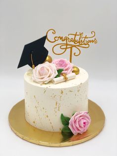 a white cake topped with pink roses and a black graduation hat