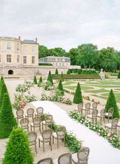 there are many chairs in the middle of this garden with flowers and bushes around it