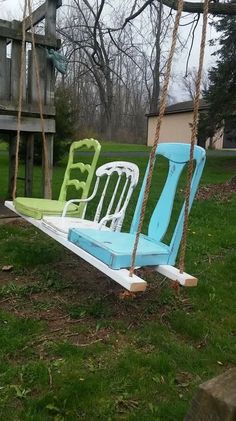 two chairs sitting on swings in the grass