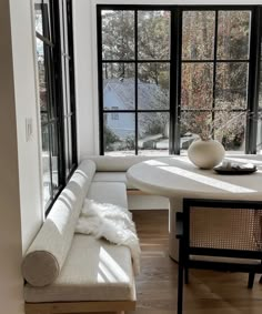 a white couch sitting in front of a window next to a table